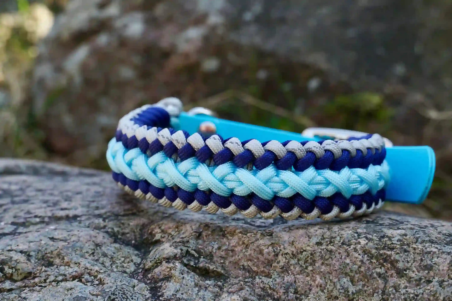 Geflochtenes Hundehalsband aus dunkelblau, hellblauen und grauen Bändern mit silberner Metallschnalle und Löchern zur Größeneinstellung.
