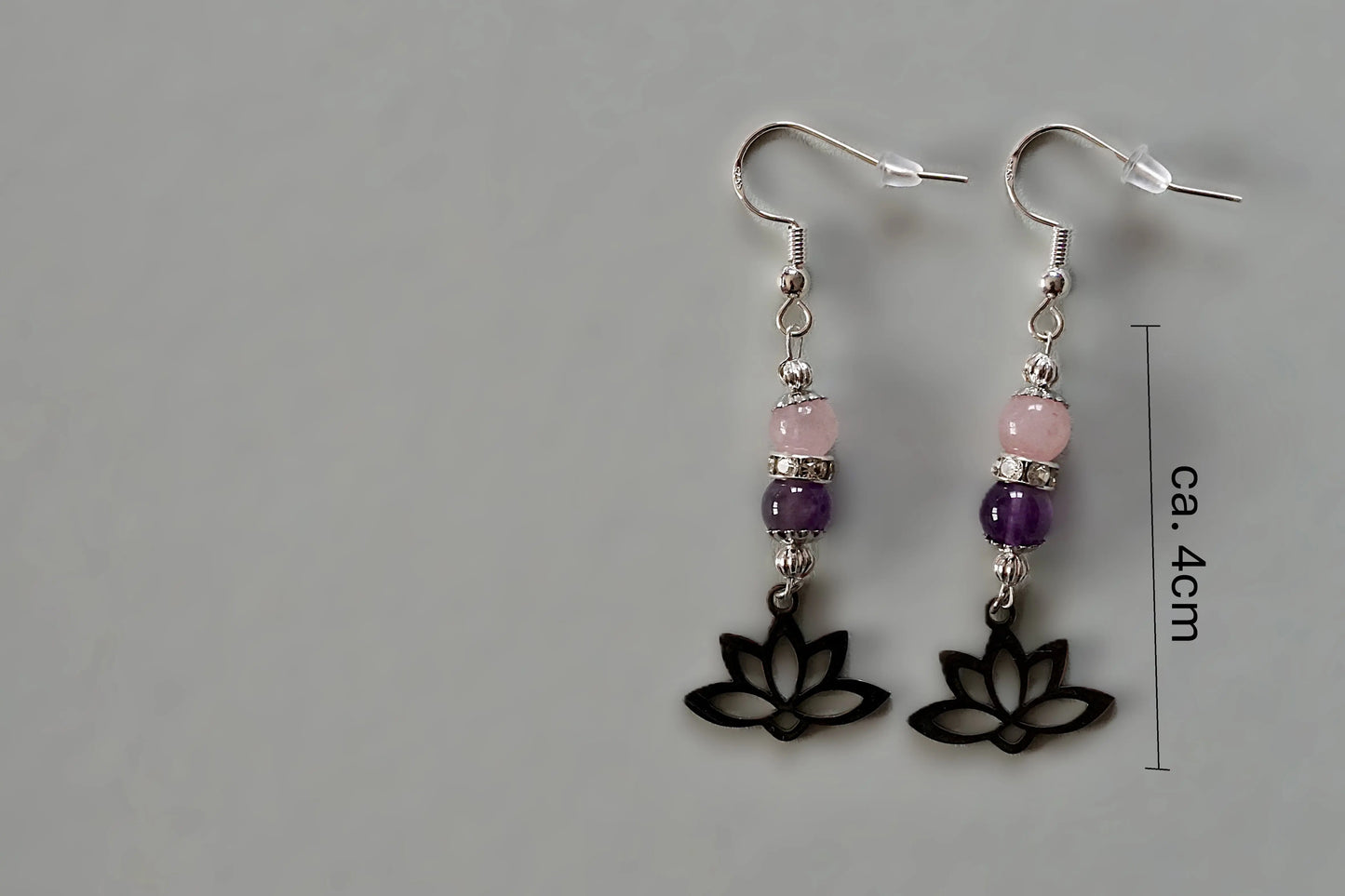 Ohrringe mit silberfarbenen Haken, zwei Edelsteinperlen in Amethyst und Rosenquarz sowie einem silberfarbenen Lotusblumenanhänger mit Maßstab