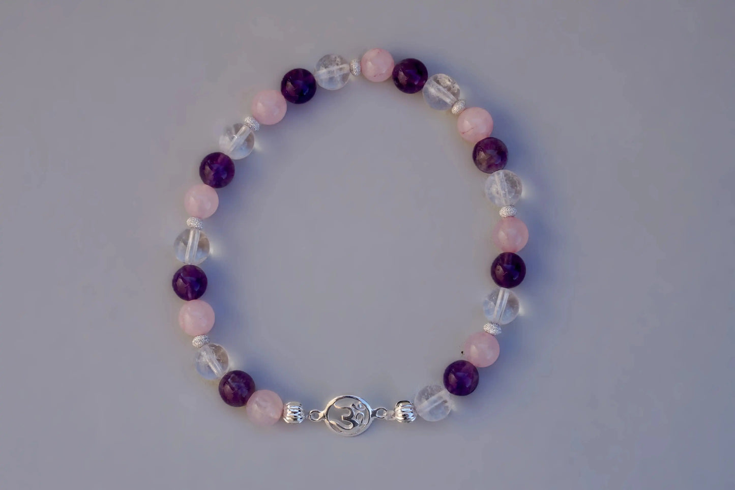 Rundes Armband aus Rosenquarz, Amethyst und Bergkristall mit silbernem Om-Anhänger und kleinen Silberperlen