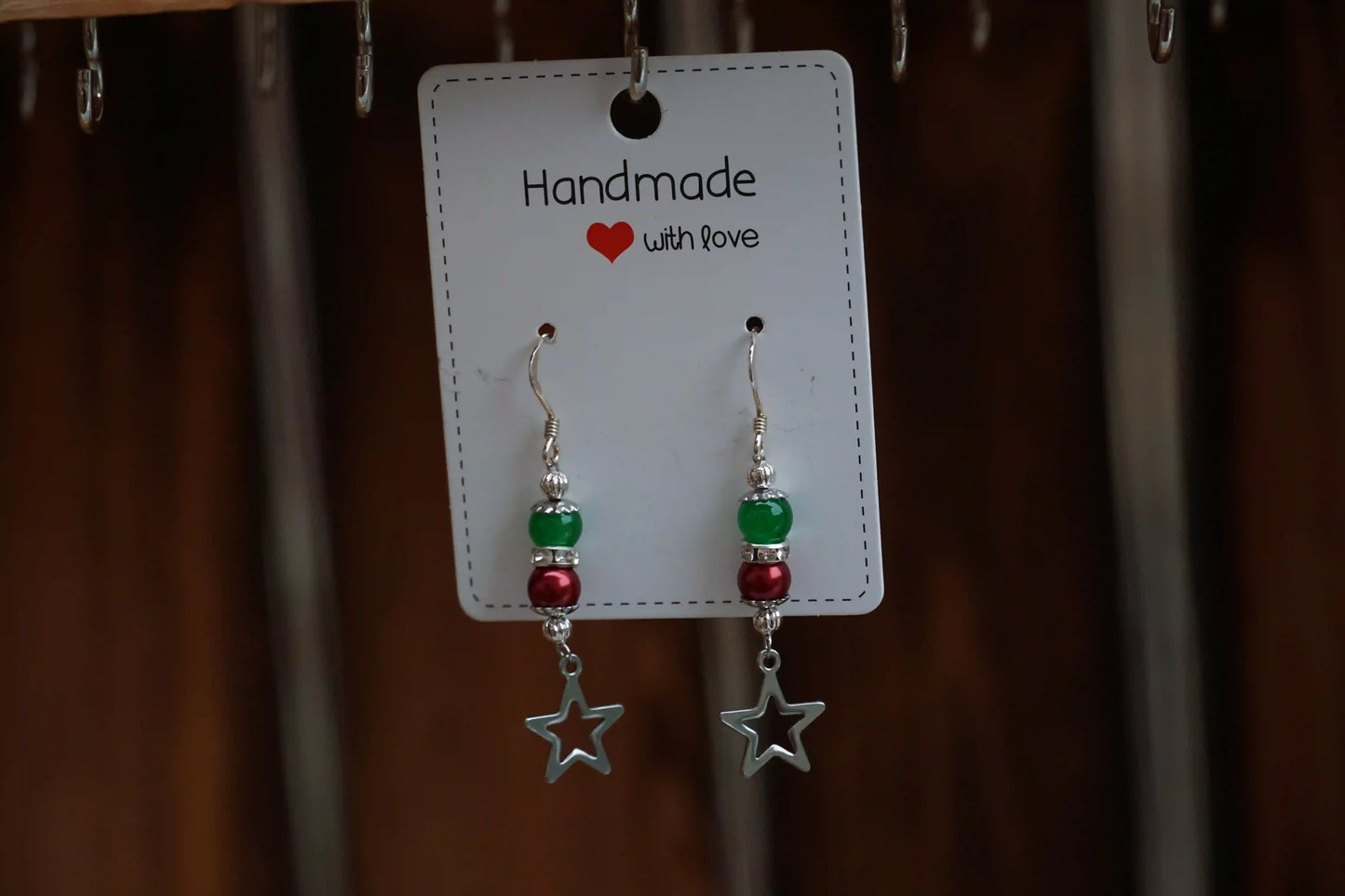 Ohrringe mit Sternanhängern, grünen und roten Perlen, an einer Karte mit der Aufschrift 'Handmade with love'.