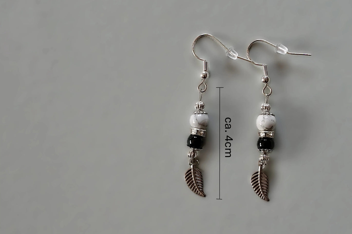 Ohrringe mit silberfarbenen Haken, zwei Edelsteinperlen in Magnesit und Turmalin sowie einem silberfarbenen Blattanhänger mit Maßstab