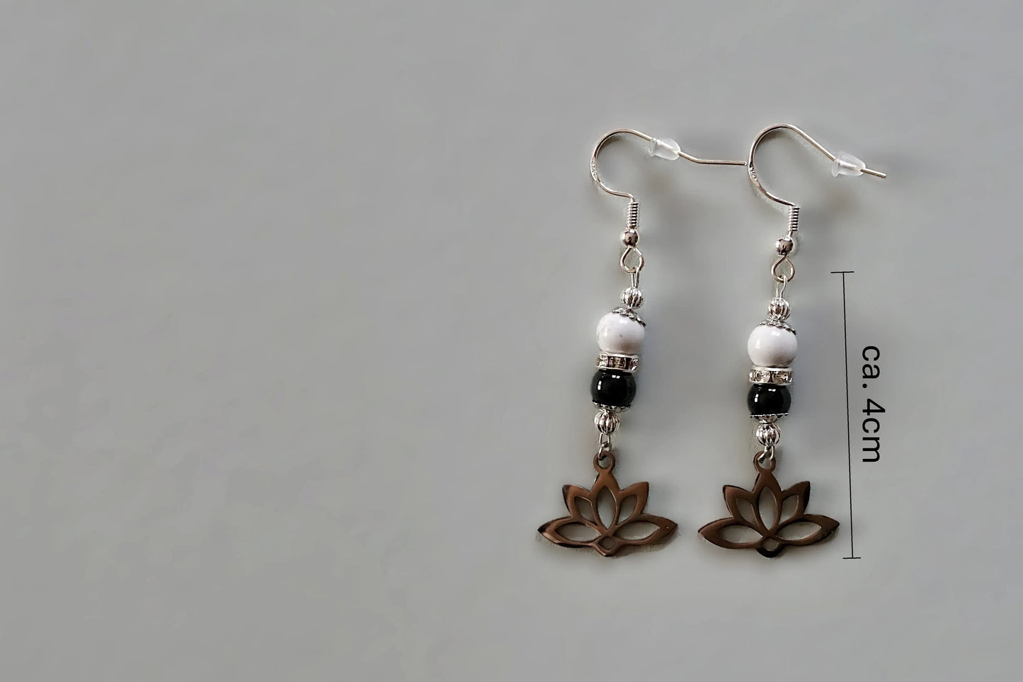 Ohrringe mit silberfarbenen Haken, zwei Edelsteinperlen in Magnesit und Turmalin sowie einem silberfarbenen Lotusblumenanhänger mit Maßstab