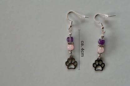 Ohrringe mit silberfarbenen Haken, zwei Edelsteinperlen in Amethyst und Rosenquarz sowie einem silberfarbenen Hundepfotenanhänger mit Maßstab