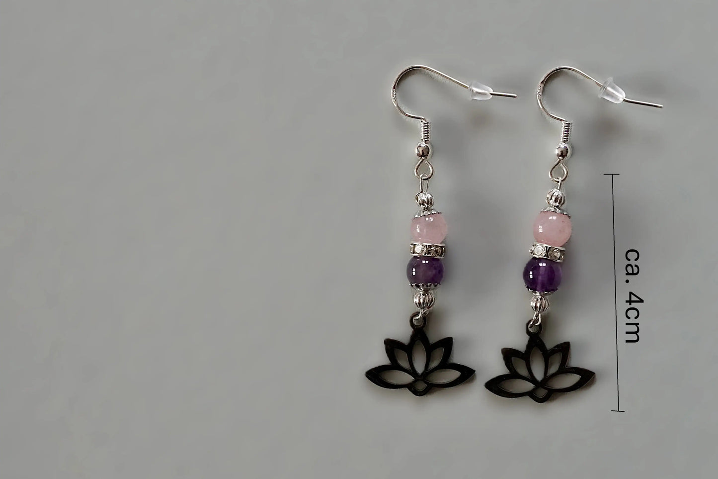 Ohrringe mit silberfarbenen Haken, zwei Edelsteinperlen in Amethyst und Rosenquarz sowie einem silberfarbenen Lotusblumenanhänger mit Maßstab