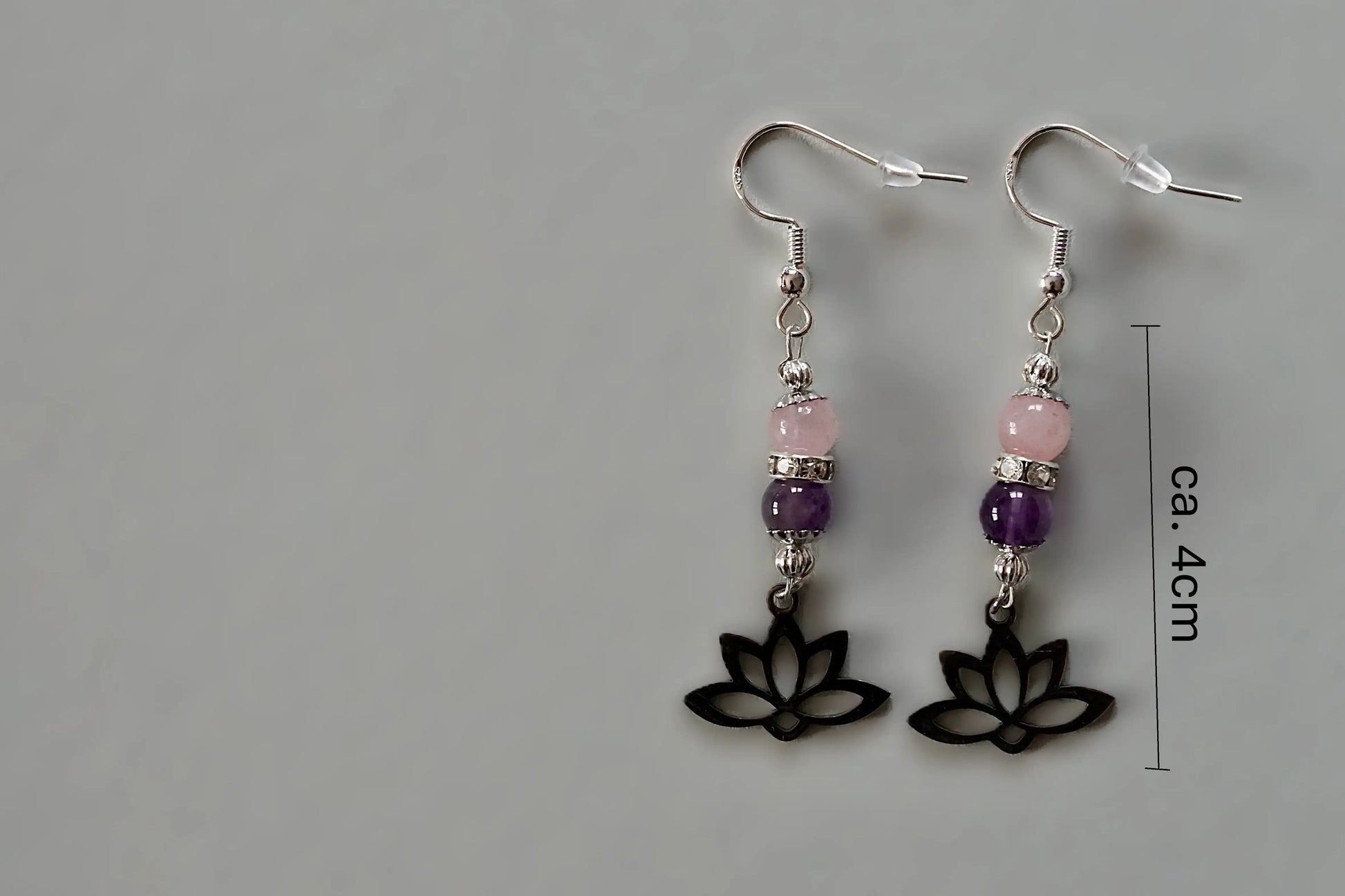 Ohrringe mit silberfarbenen Haken, zwei Edelsteinperlen in Amethyst und Rosenquarz sowie einem silberfarbenen Lotusblumenanhänger mit Maßstab