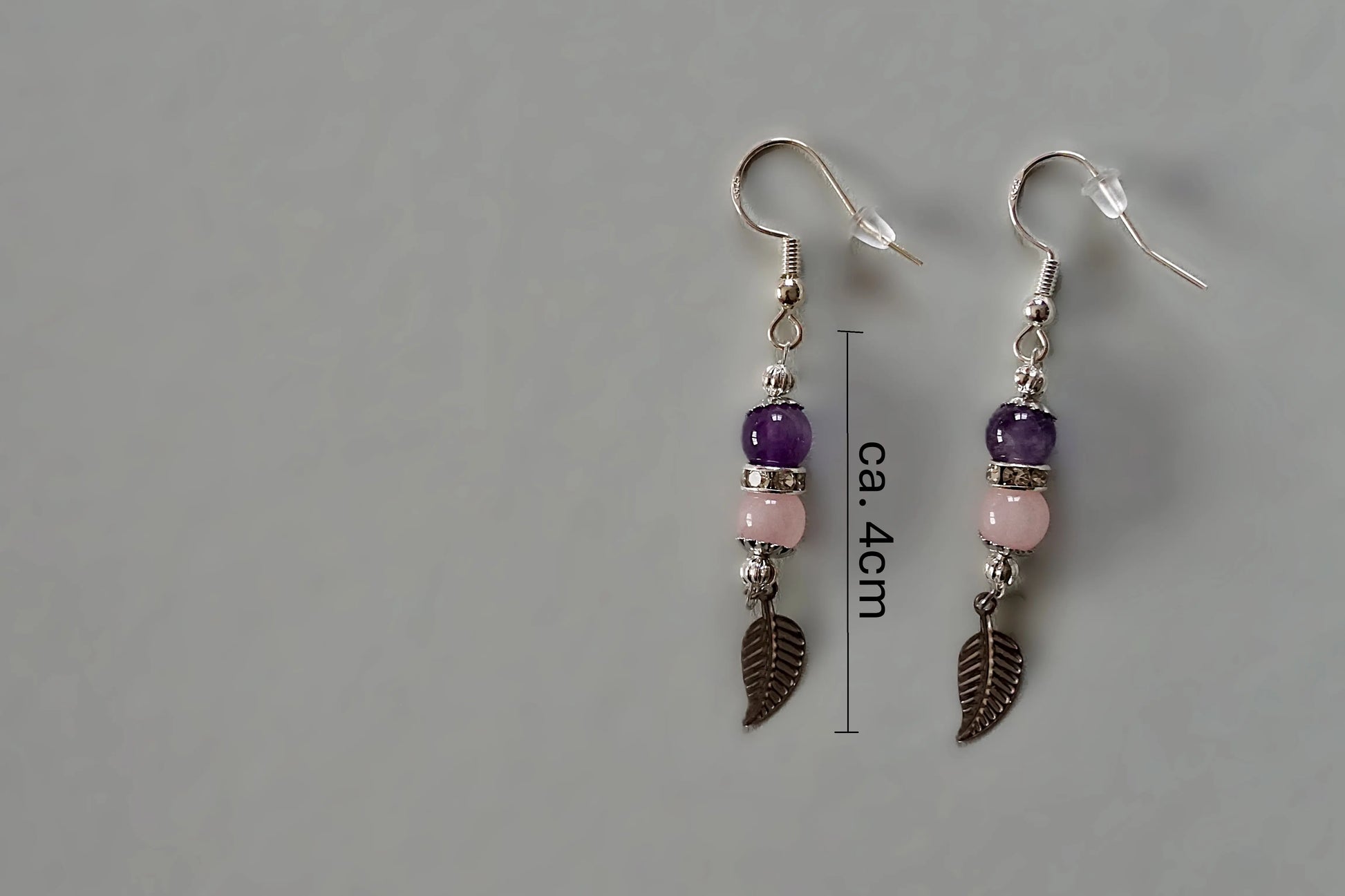 Ohrringe mit silberfarbenen Haken, zwei Edelsteinperlen in Amethyst und Rosenquarz sowie einem silberfarbenen Blattanhänger mit Maßstab