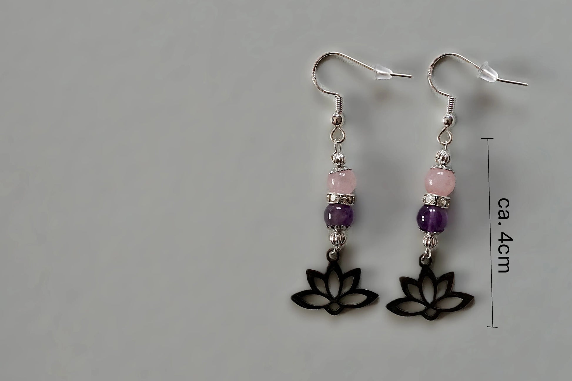 Ohrringe mit silberfarbenen Haken, zwei Edelsteinperlen in Amethyst und Rosenquarz sowie einem silberfarbenen Lotusblumenanhänger mit Maßstab