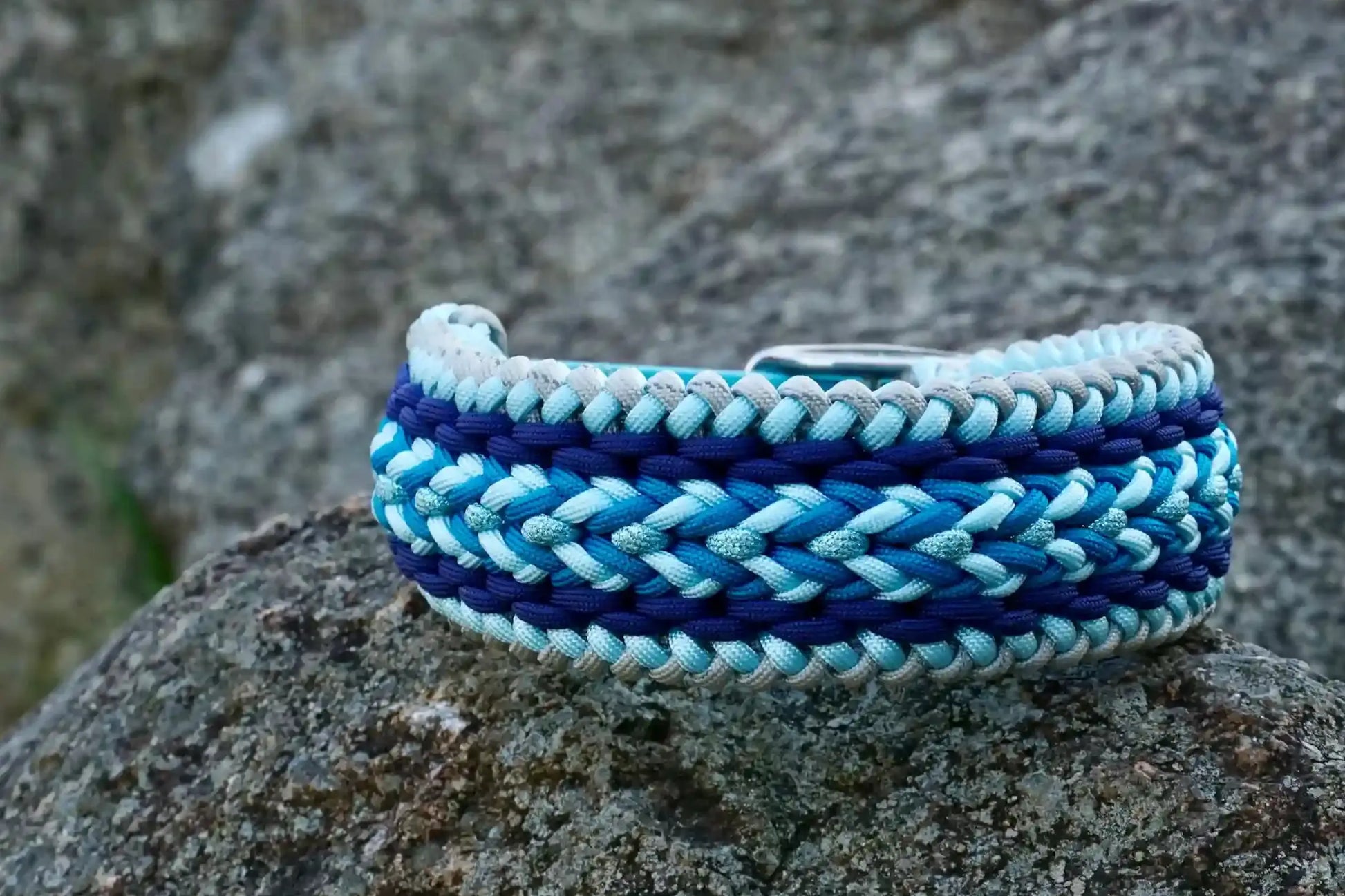 Geflochtenes Hundehalsband aus dunkelblau, hellblauen und grauen Bändern mit silberner Metallschnalle und Löchern zur Größeneinstellung.