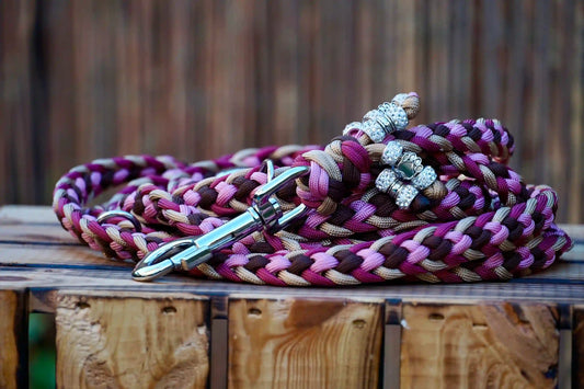 Geflochtene Paracord Hundeleine in Braun- und Pinktönen mit Metallkarabiner und Schmuckperlen am Griff auf Holzkiste