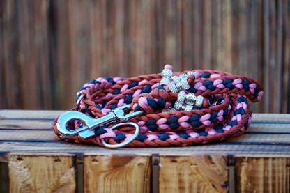 Geflochtene Paracord Hundeleine in Bronze, rosa und Anthrazittönen mit Metallkarabiner und Schmuckperlen am Griff auf holzkiste