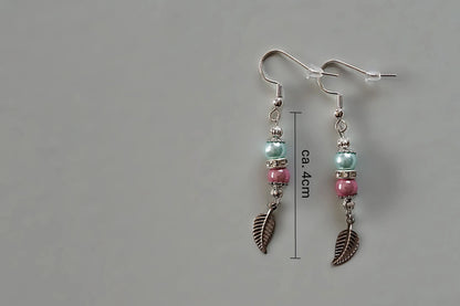Ohrringe mit silberfarbenen Haken, zwei Perlen in Türkis und Rosa sowie einem silberfarbenen Blattanhänger mit Maßstab