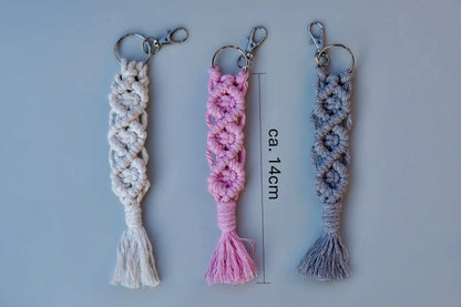 Drei Makramee-Schlüsselanhänger in Weiß, Rosa und Grau mit Knotenmustern und Fransen, jeweils mit Metallring und Karabinerhaken