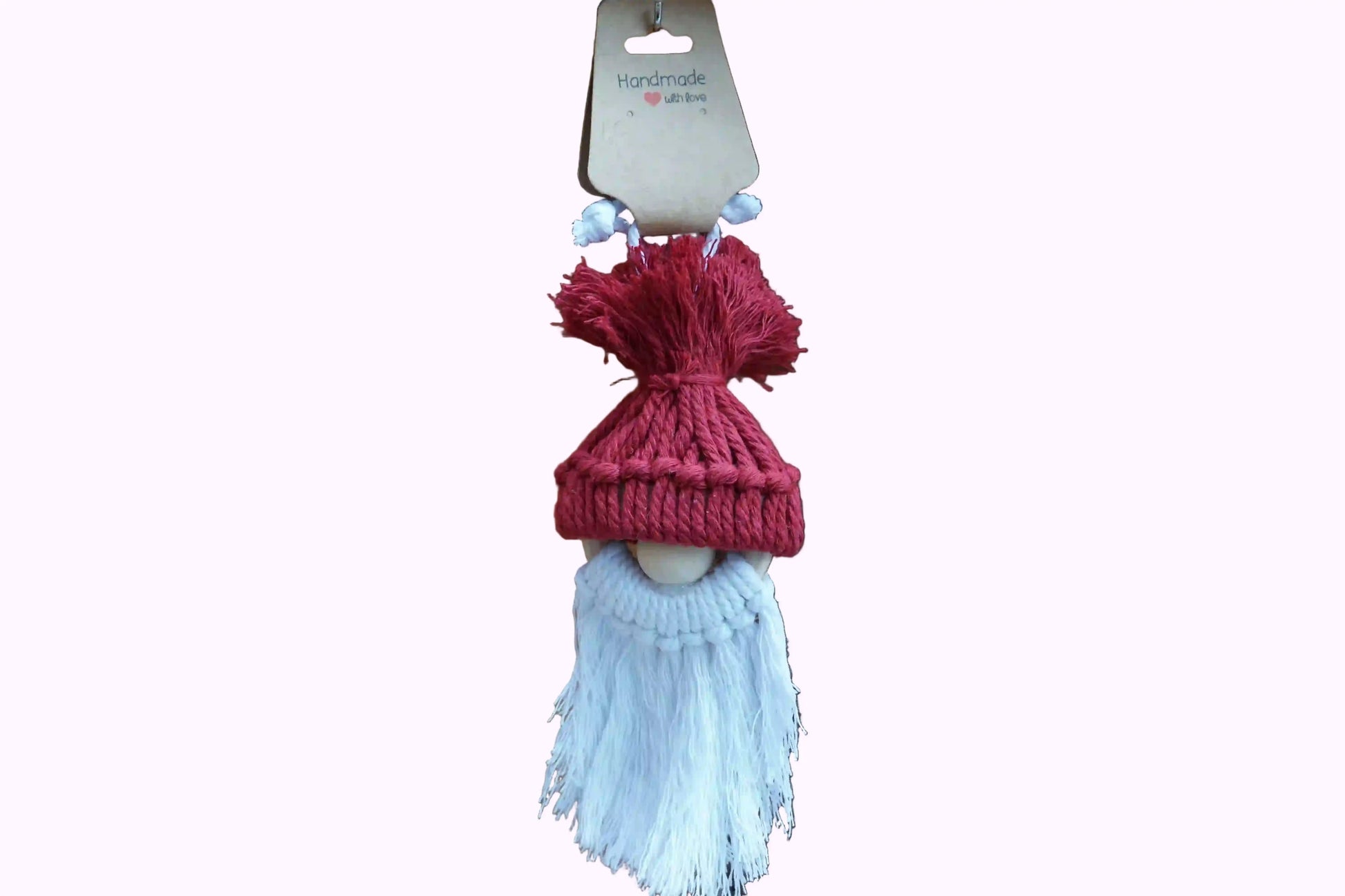 Burgunder gestrickte Mütze mit Bommel auf einer Holzfigur mit weißem, langem Bart, hängend vor Holzlatten.