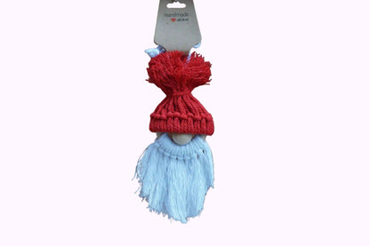 Rote gestrickte Mütze mit Bommel auf einer Holzfigur mit weißem, langem Bart