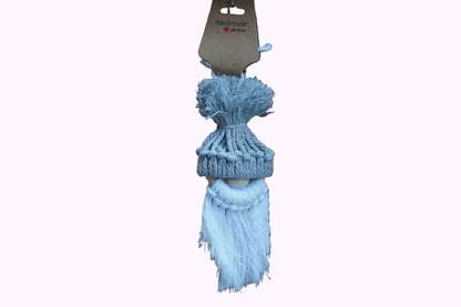 graue gestrickte Mütze mit Bommel auf einer Holzfigur mit weißem, langem Bart