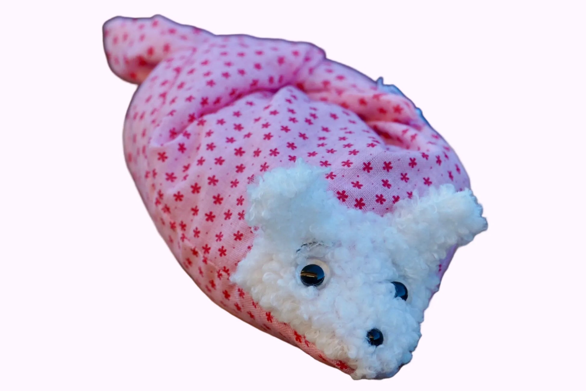 Kuscheltier in Form eines weißen Hasenkopfes mit Knopfaugen, eingewickelt in rosa Stoff mit Sternen 